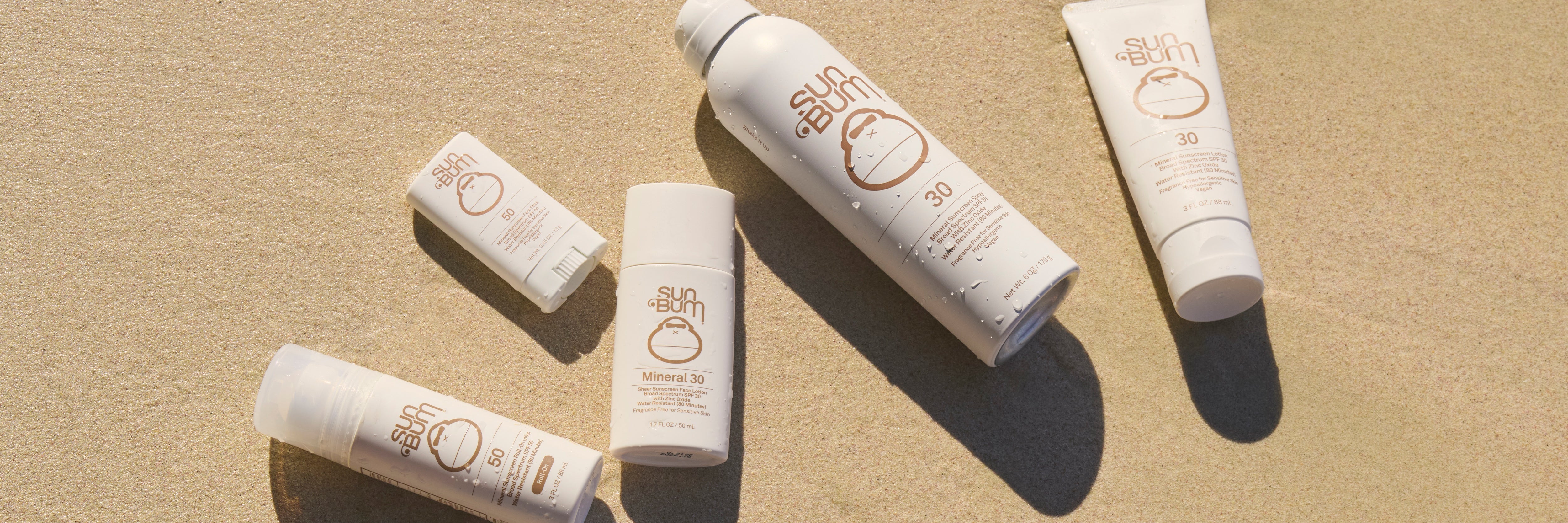 Sunscreen products on a beige sand background