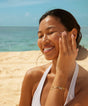 Woman applying sunscreen on a beach with ocean view