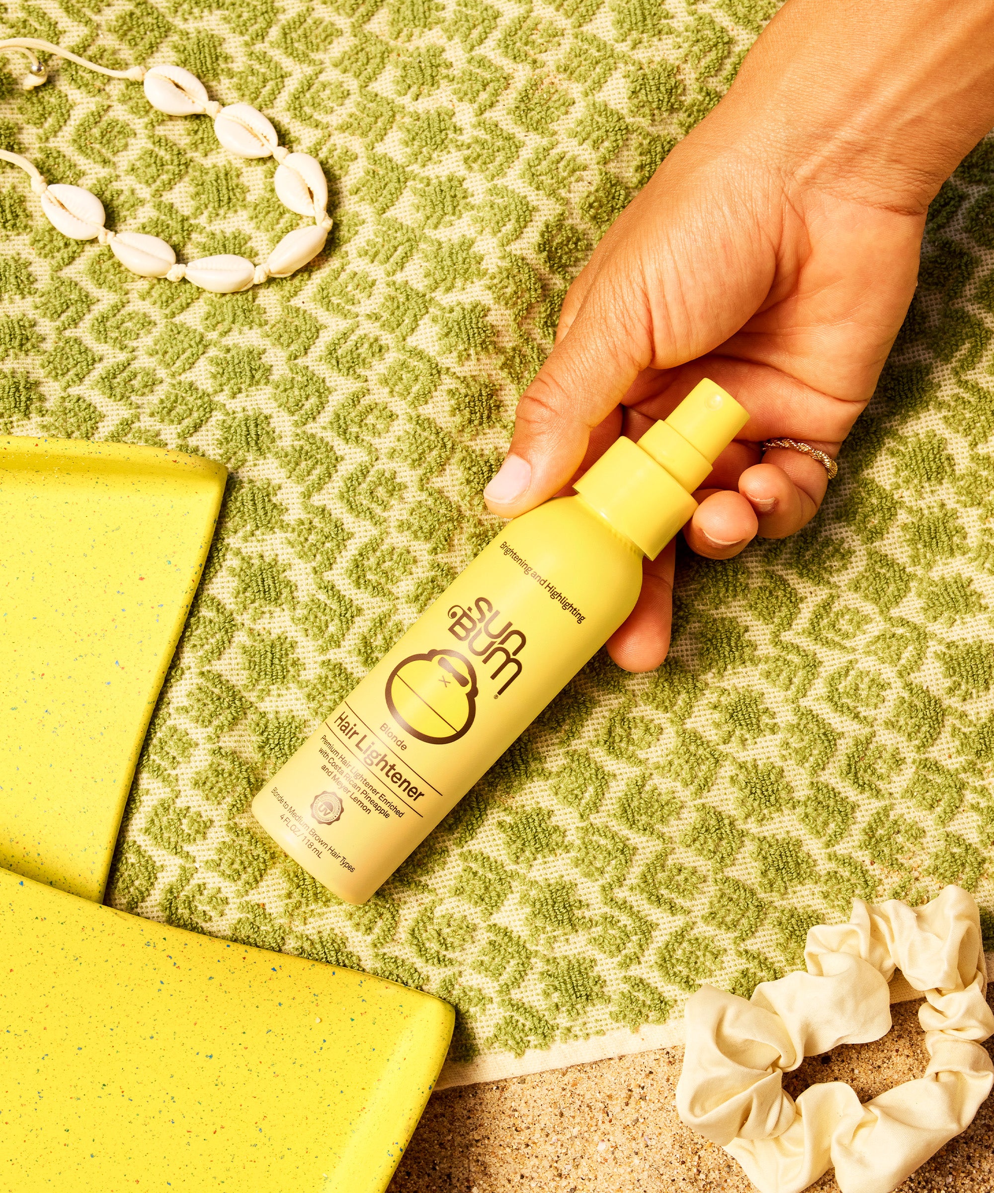 Hand holding a yellow bottle with text on a green textured surface