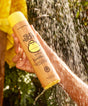 Person holding a bottle of Sun Bum conditioner under a shower