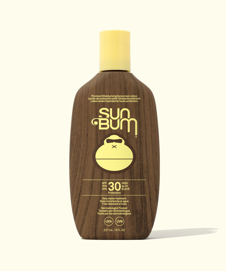 Sun Bum sunscreen bottle with wooden texture and yellow cap on a white background