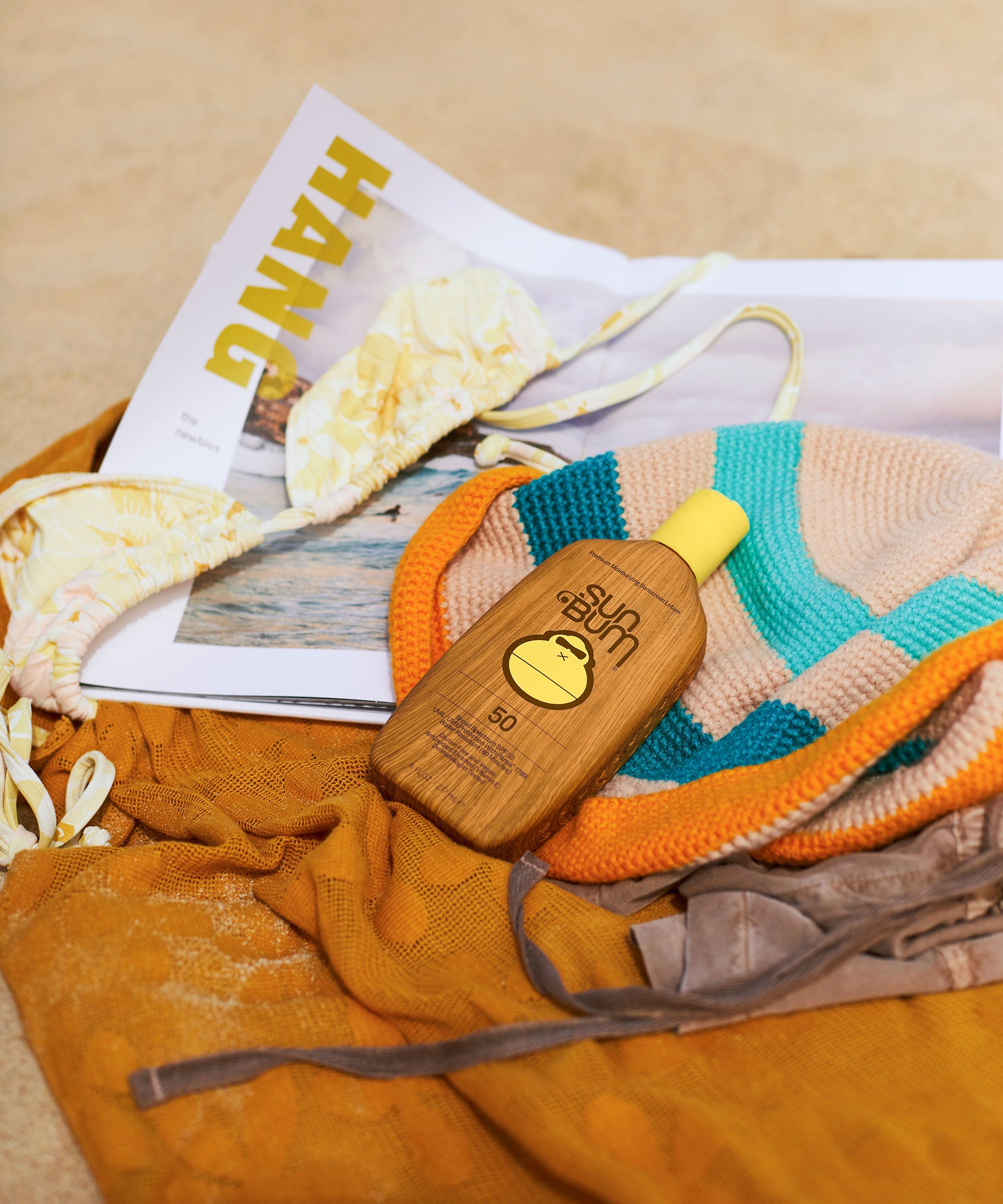 Wooden sun screen bottle with yellow label on a magazine and towel