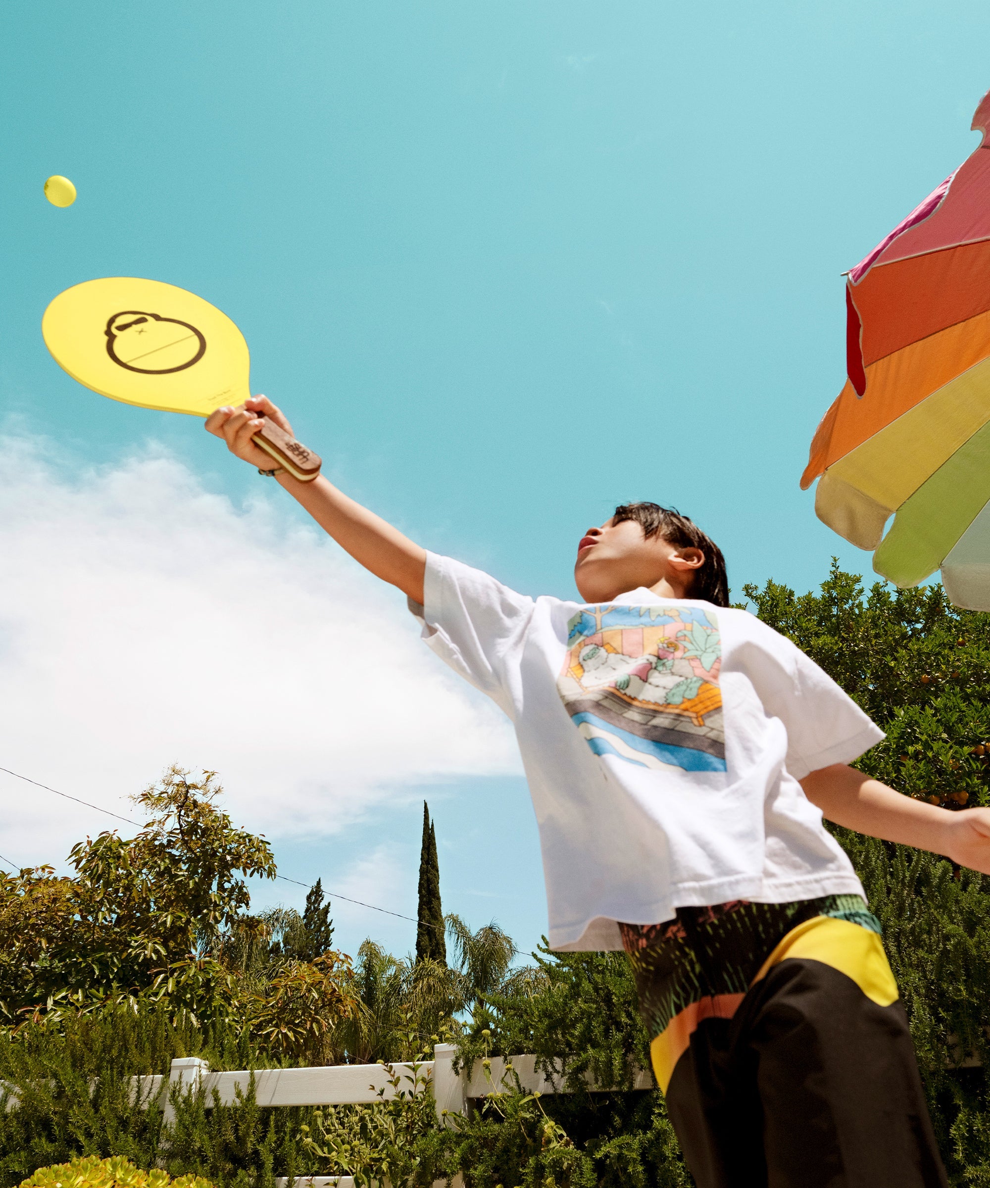 Kid plays paddle ball under sunny skies using yellow Sonny gear paddle - Sonny Gear Collection - Sun Bum